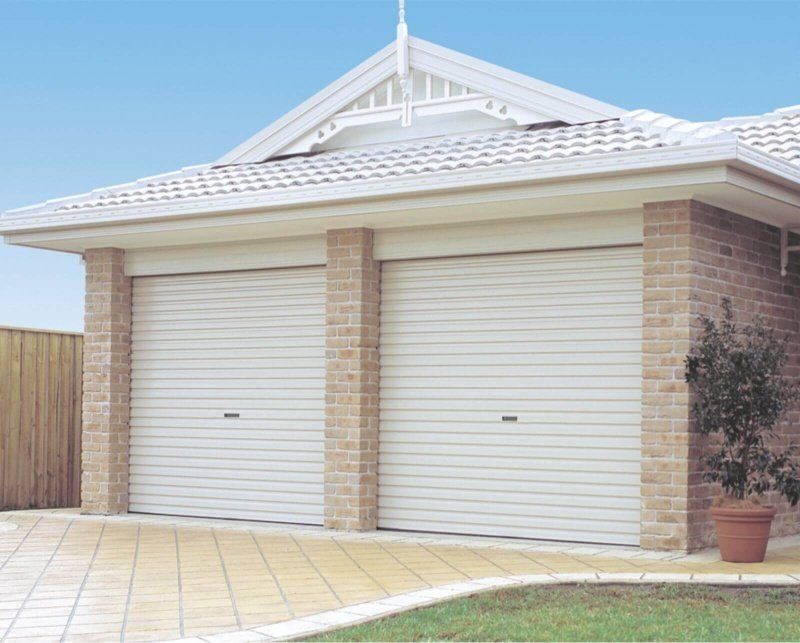 A house with two garage doors and a potted plant in front of it