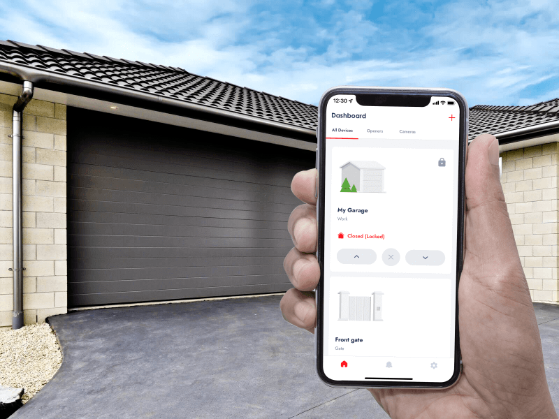 A person is holding a cell phone in front of a garage door.