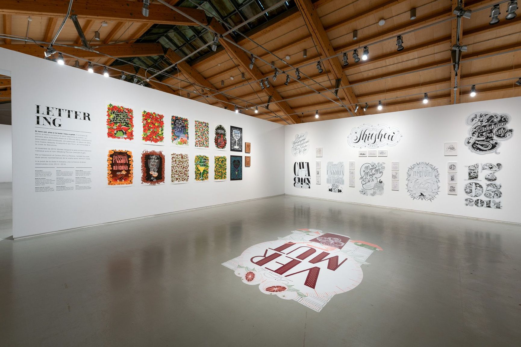 Art gallery interior with white walls displaying colorful print artworks and a large floor mural.