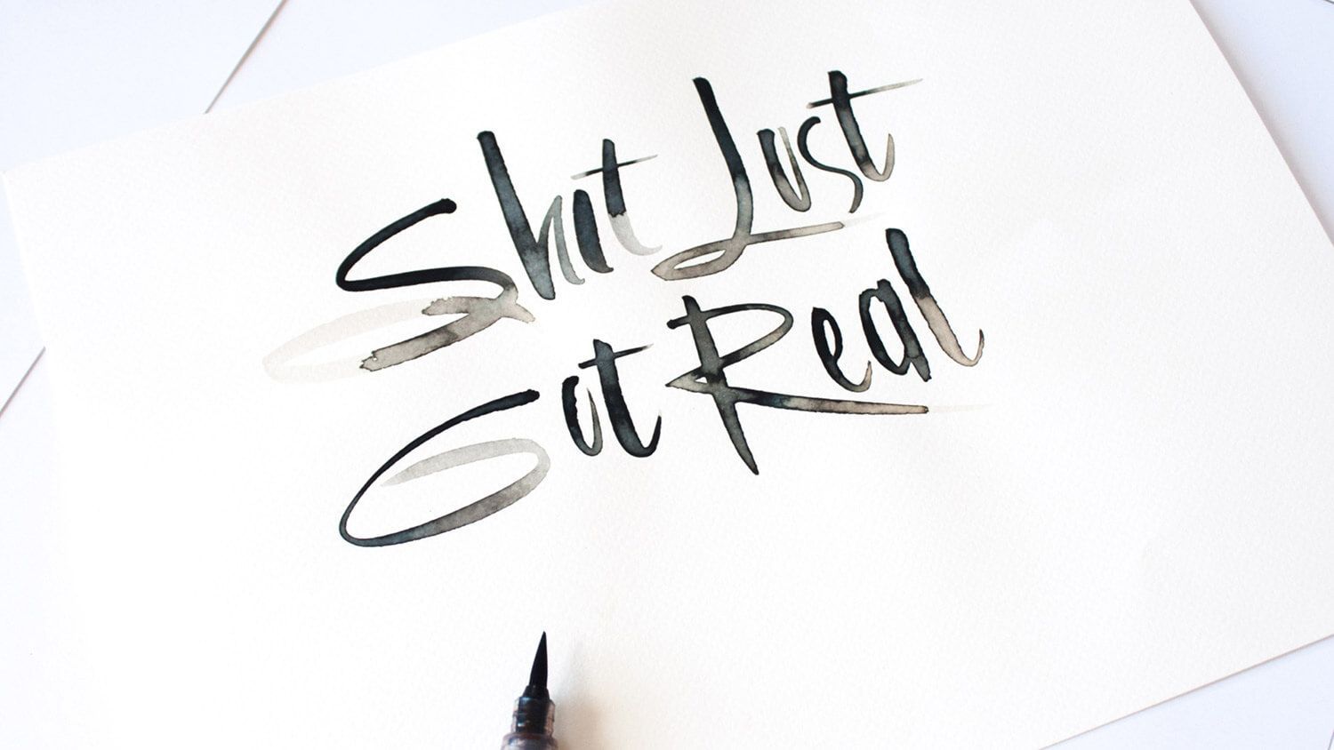 Handwritten “She Just Stared” in black ink on white paper, with a pen tip visible at the bottom