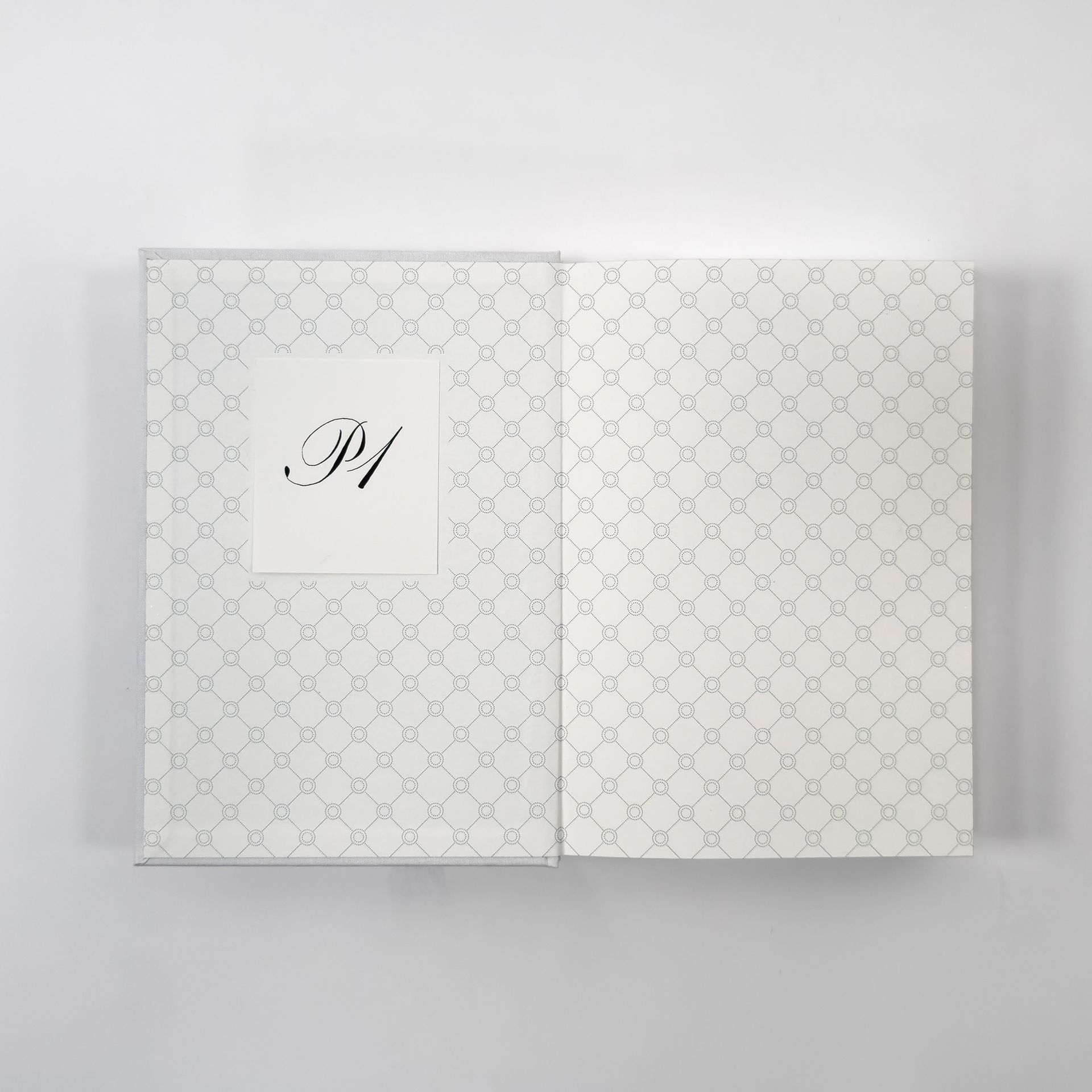 Patterned white folded card with a small square monogram label on the left side