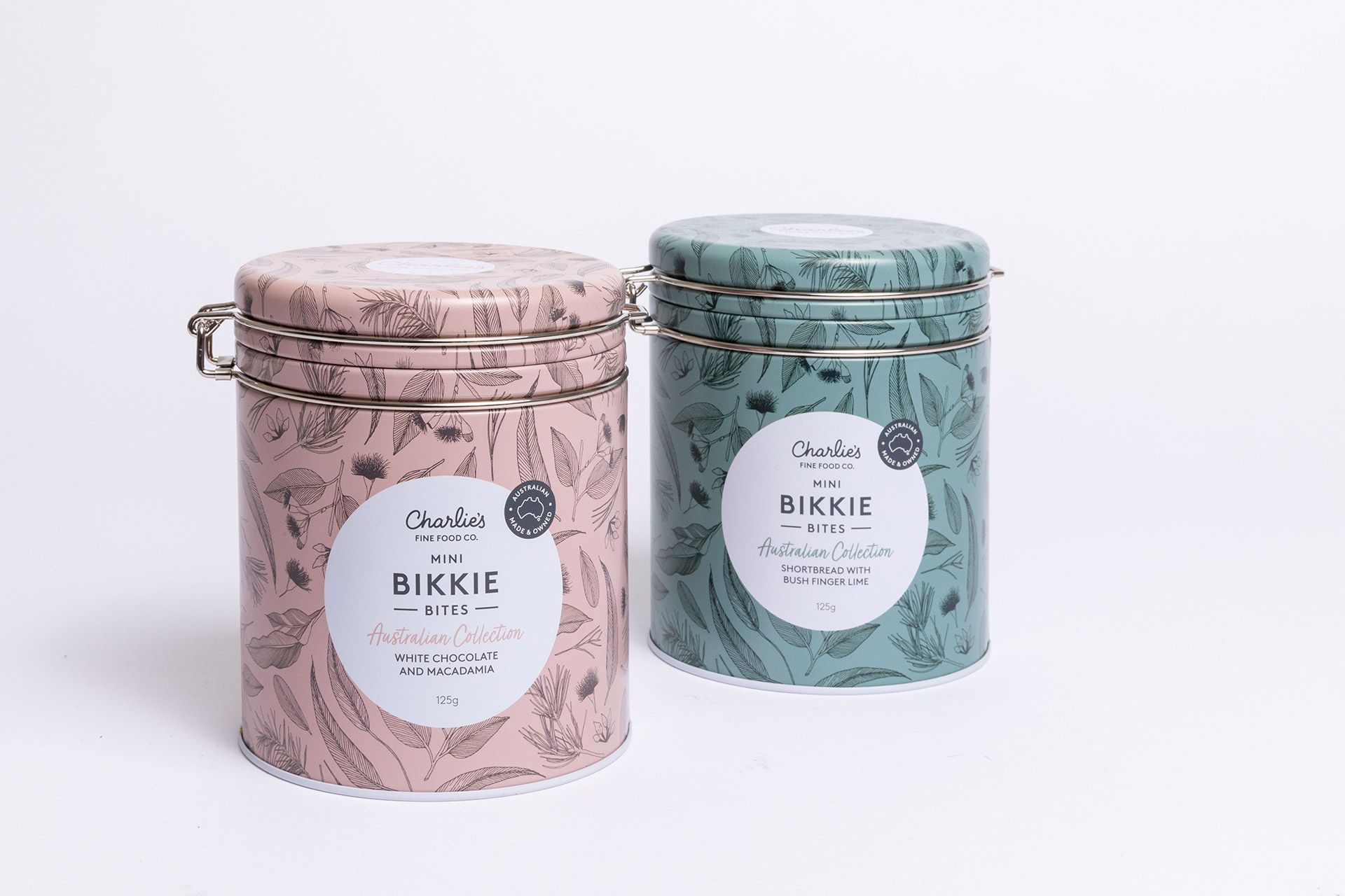 Two pastel floral gift tins, one pink and one blue, with round labels on a white background