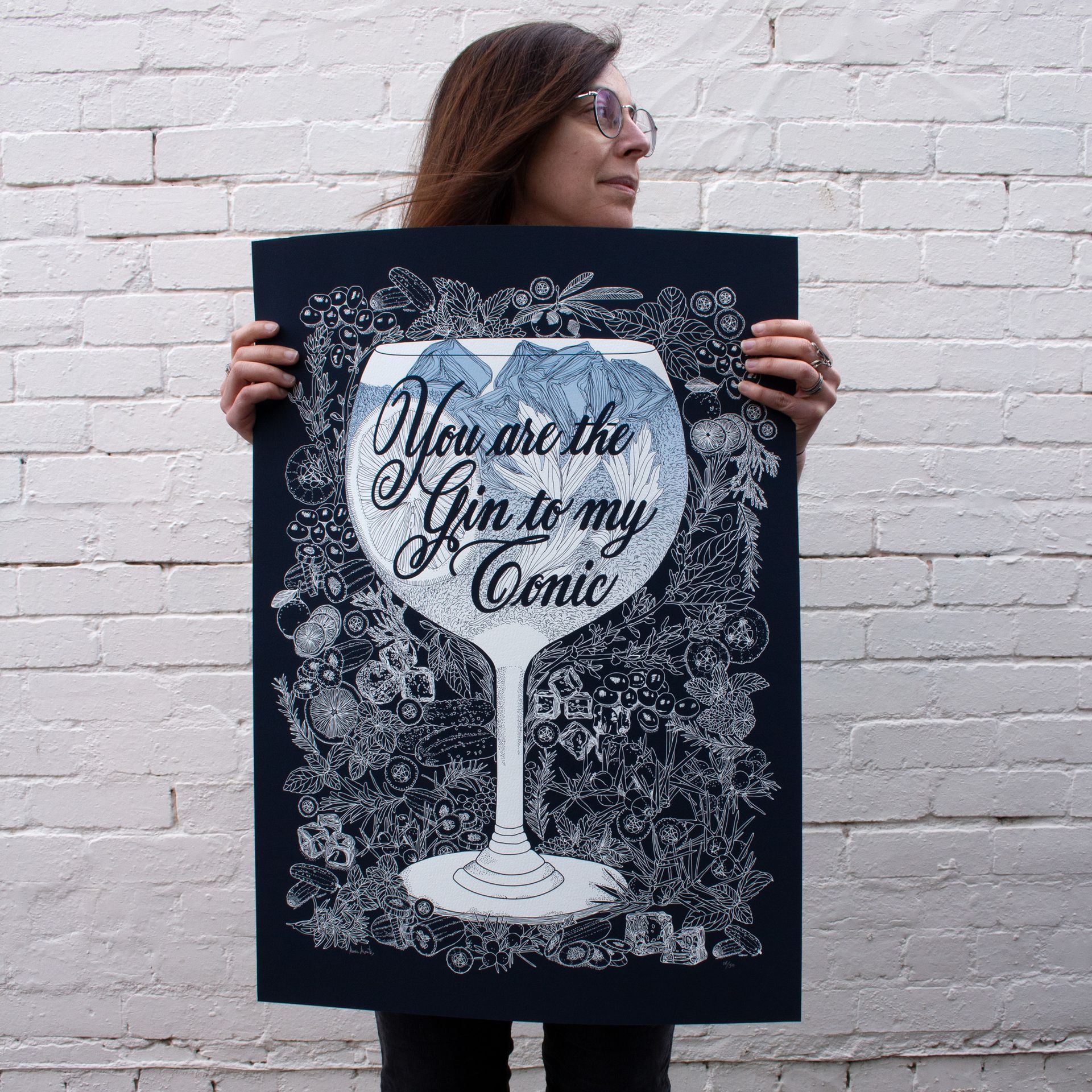Person holding a black poster with a white martini glass and the words “You are the Gin to my Tonic.”