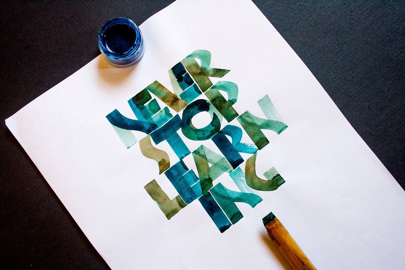 Blue and green watercolor lettering on white paper reads 