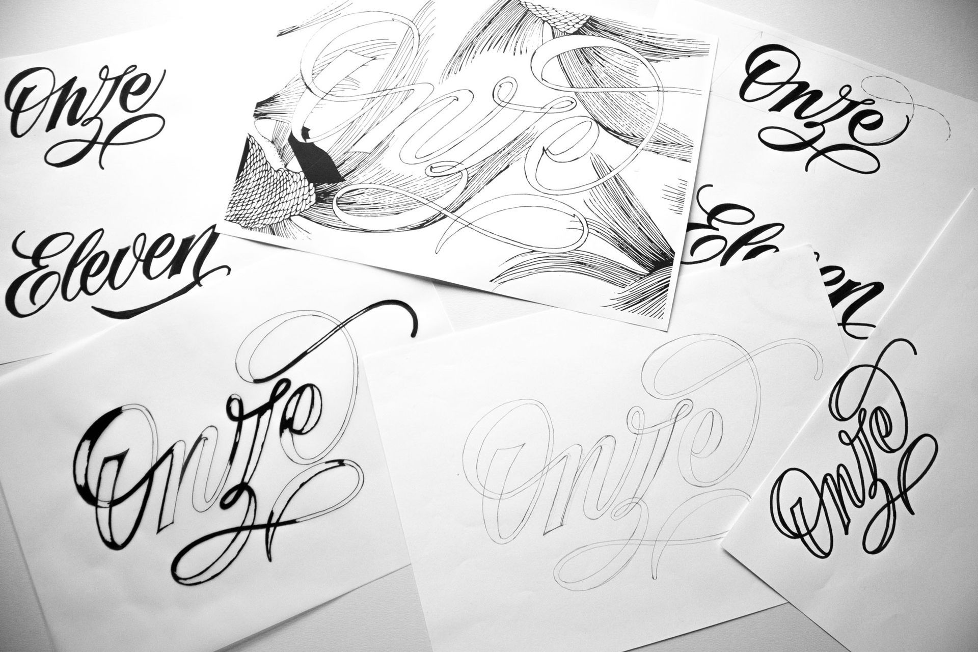 A collection of white papers featuring multiple sketches of the word 
