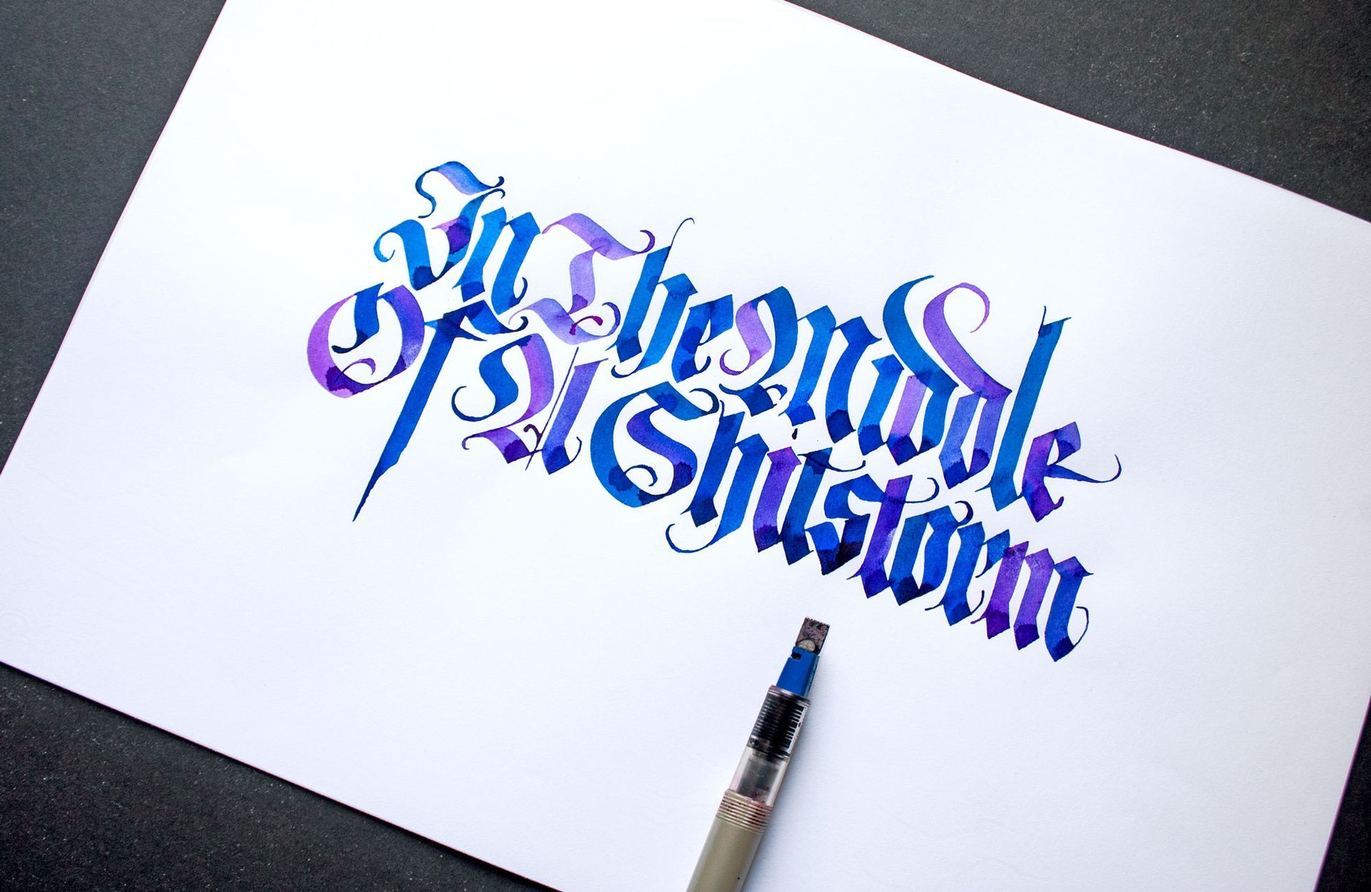 Blue and purple calligraphy on white paper with a pen nearby