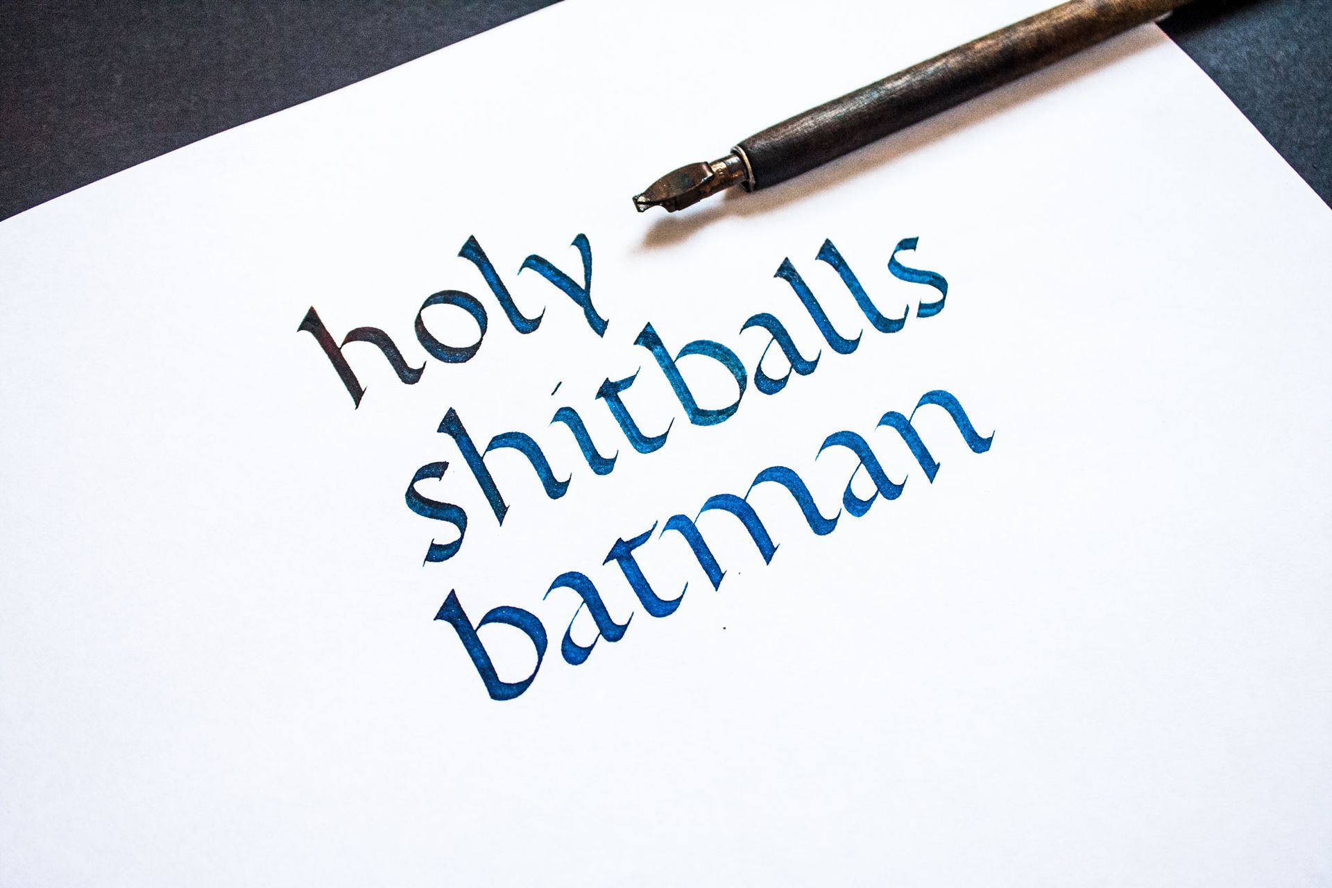 Pen writing “holy shitballs batman” on white paper
