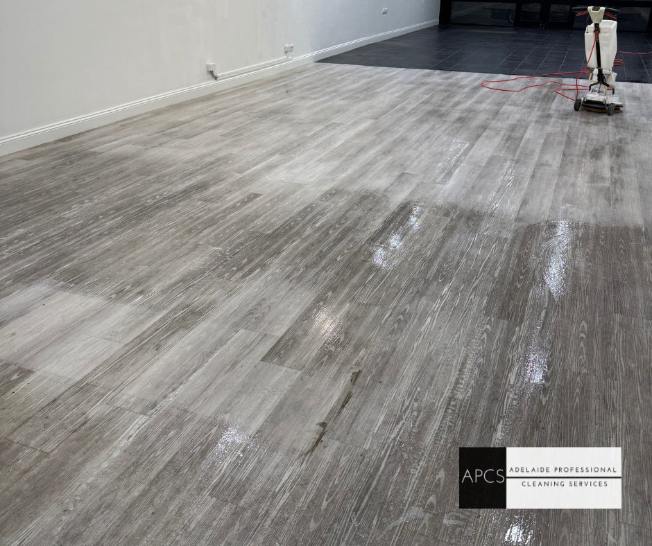 A person is cleaning a wooden floor in a room.