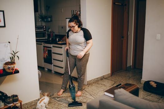 A woman is cleaning the floor with a vacuum cleaner in a living room.