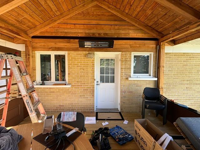 Véranda fermée en bois, avec fenêtres et porte. Une échelle et divers objets sont présents, ce qui laisse supposer que des travaux sont en cours.