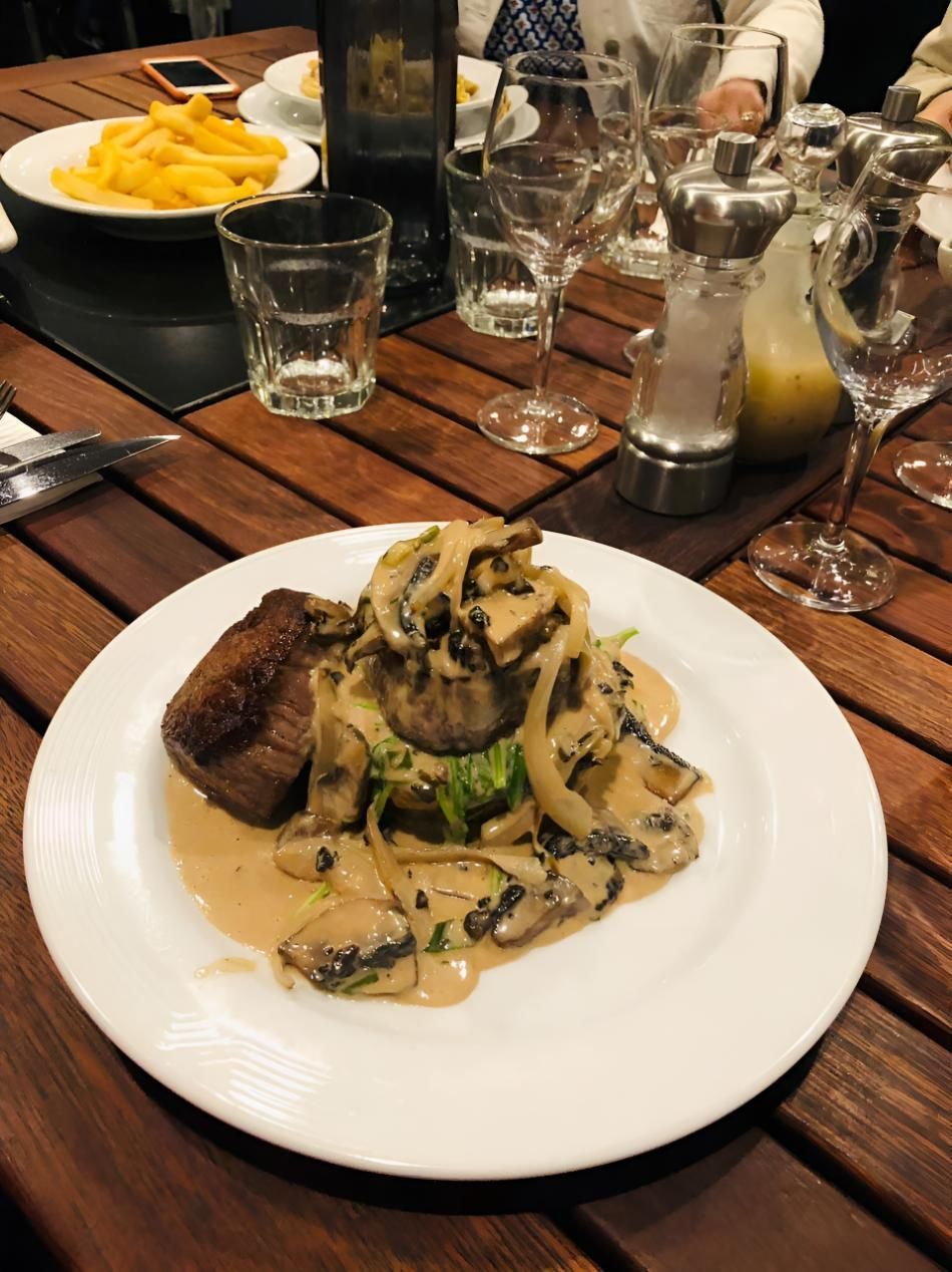 A Plate Of Food Is Sitting On A Wooden Table — Stonegrill Huskisson In Huskisson, NSW