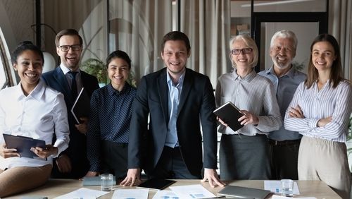 A group of business people are posing for a picture in front of a table.