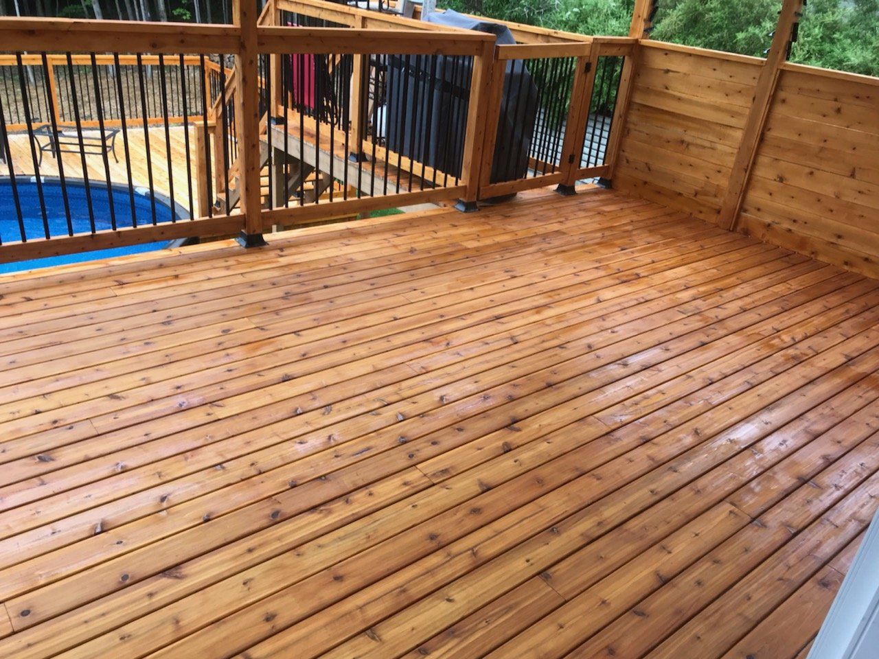 Une terrasse en bois avec une balustrade et une piscine en arrière-plan.