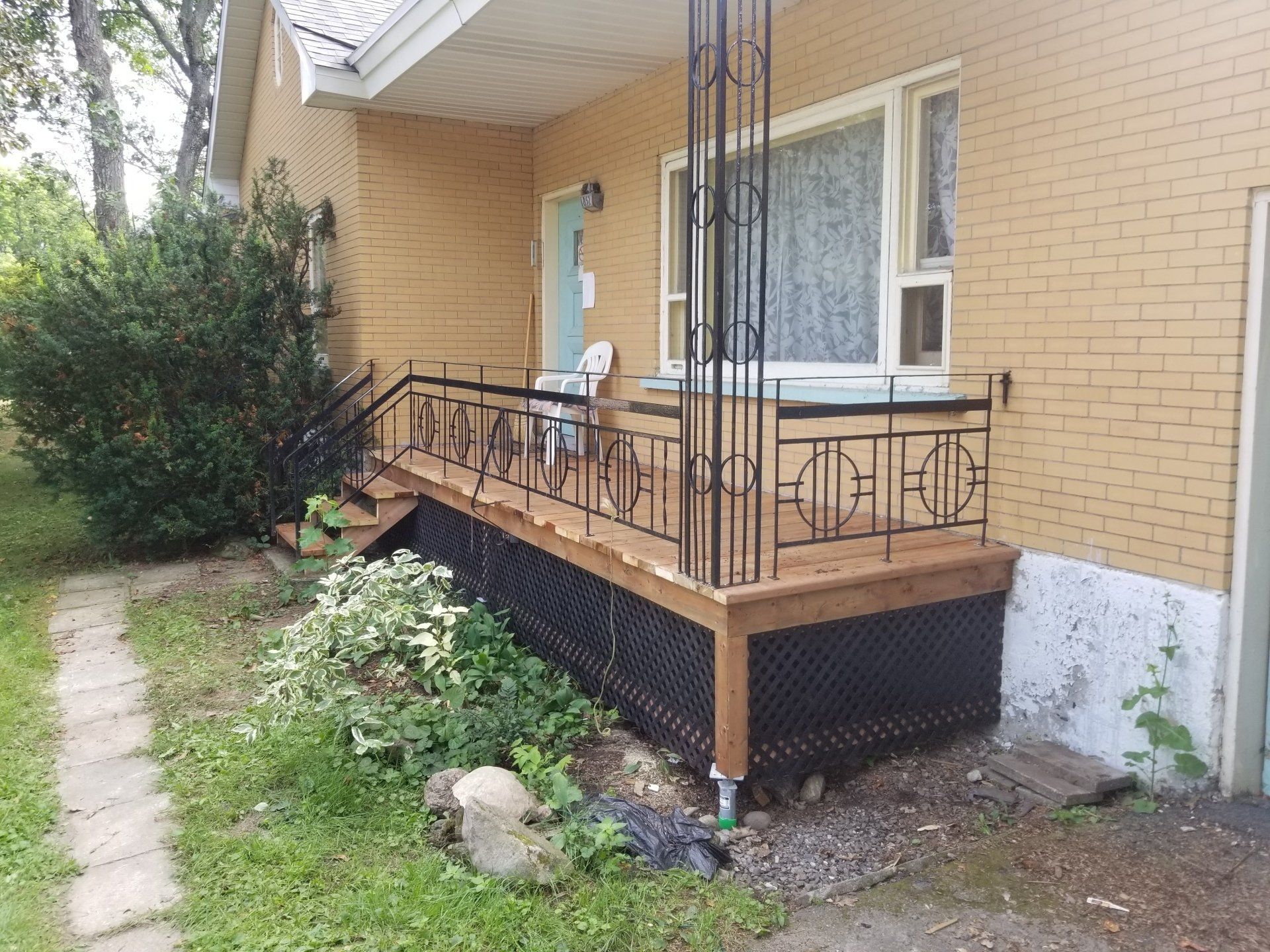Une maison en brique avec un porche et des escaliers en bois