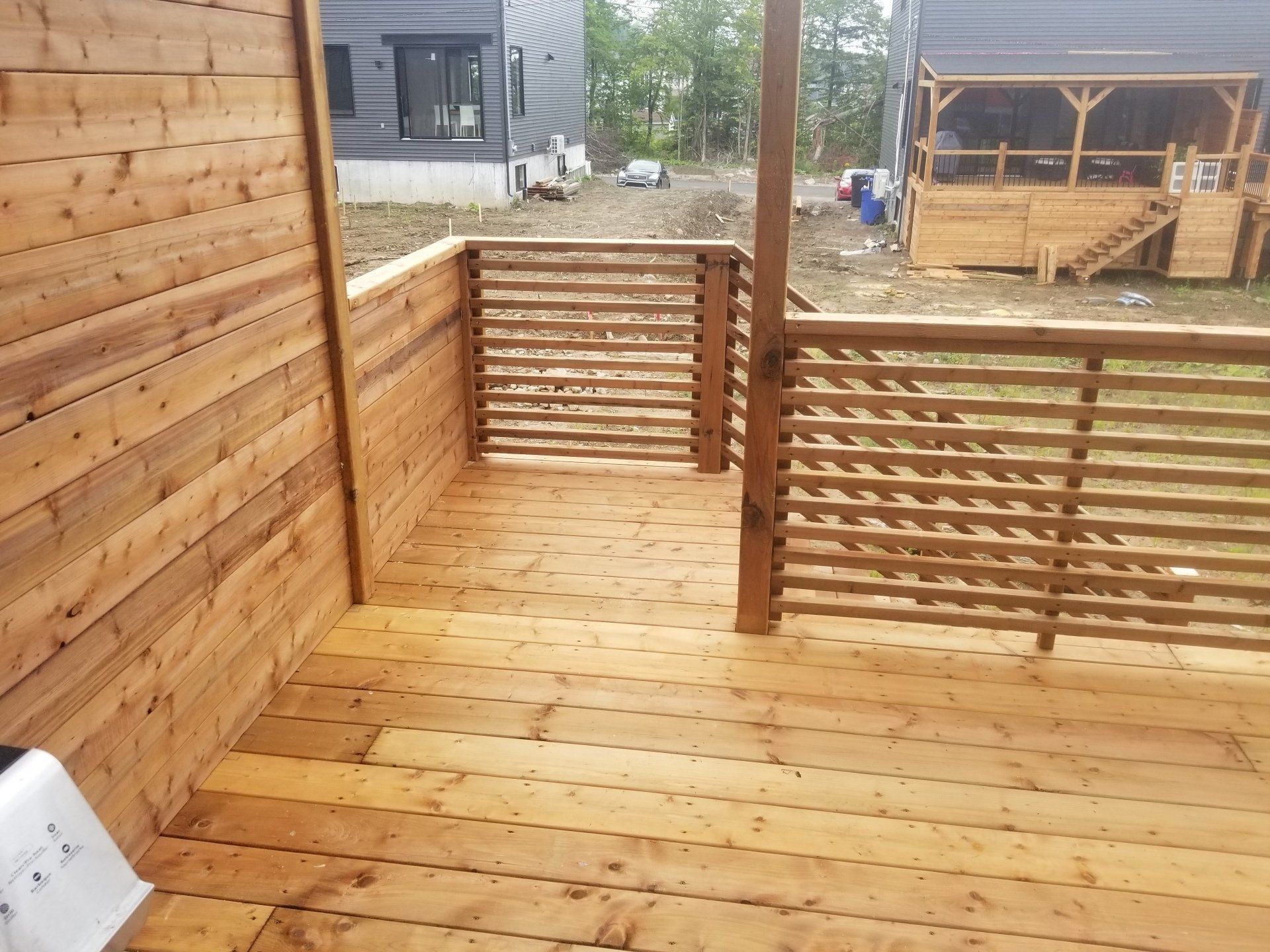 Une terrasse en bois avec une balustrade et une maison en arrière-plan.