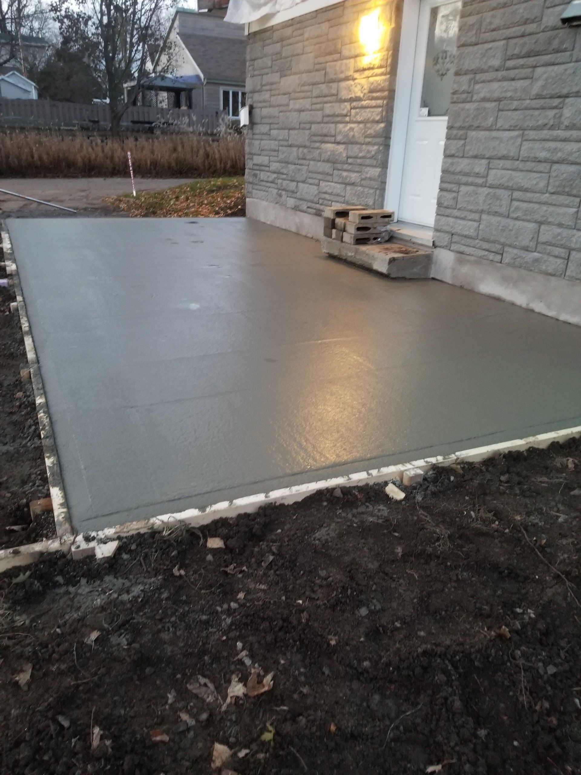 Une allée en béton est en cours de construction devant une maison en briques.