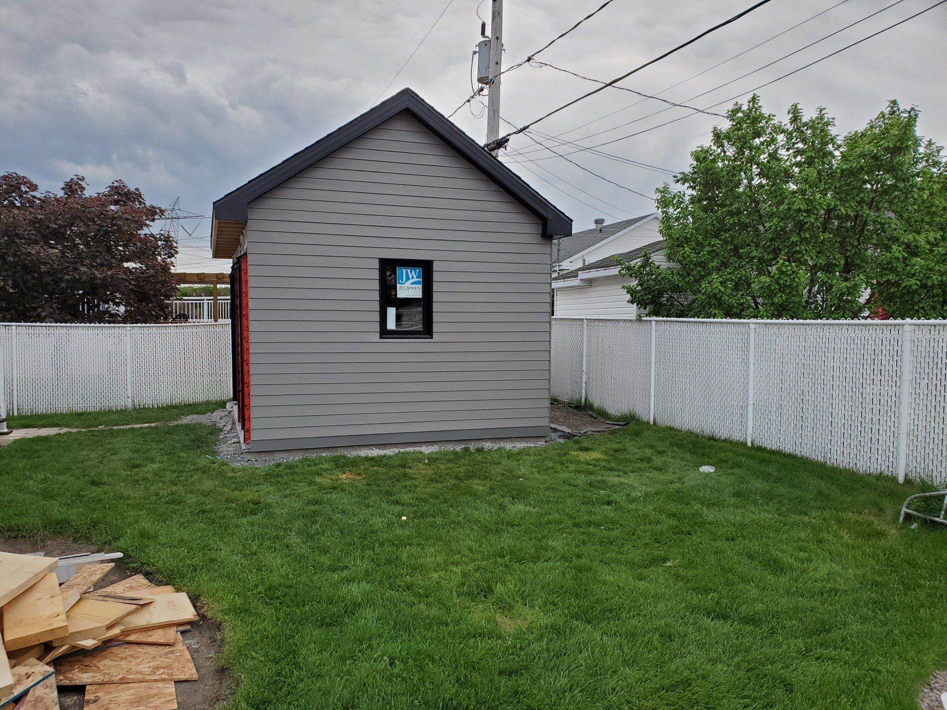 Une petite maison est située au milieu d'une cour verdoyante.