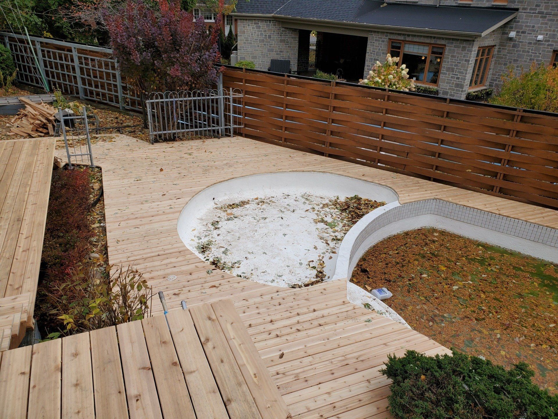 Une terrasse en bois avec un bain à remous au milieu.