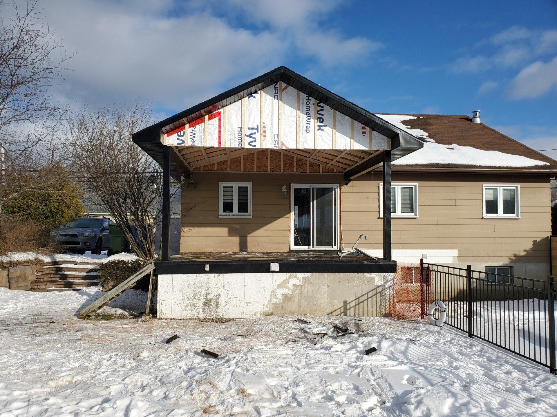 Une maison avec un porche et une clôture dans la neige