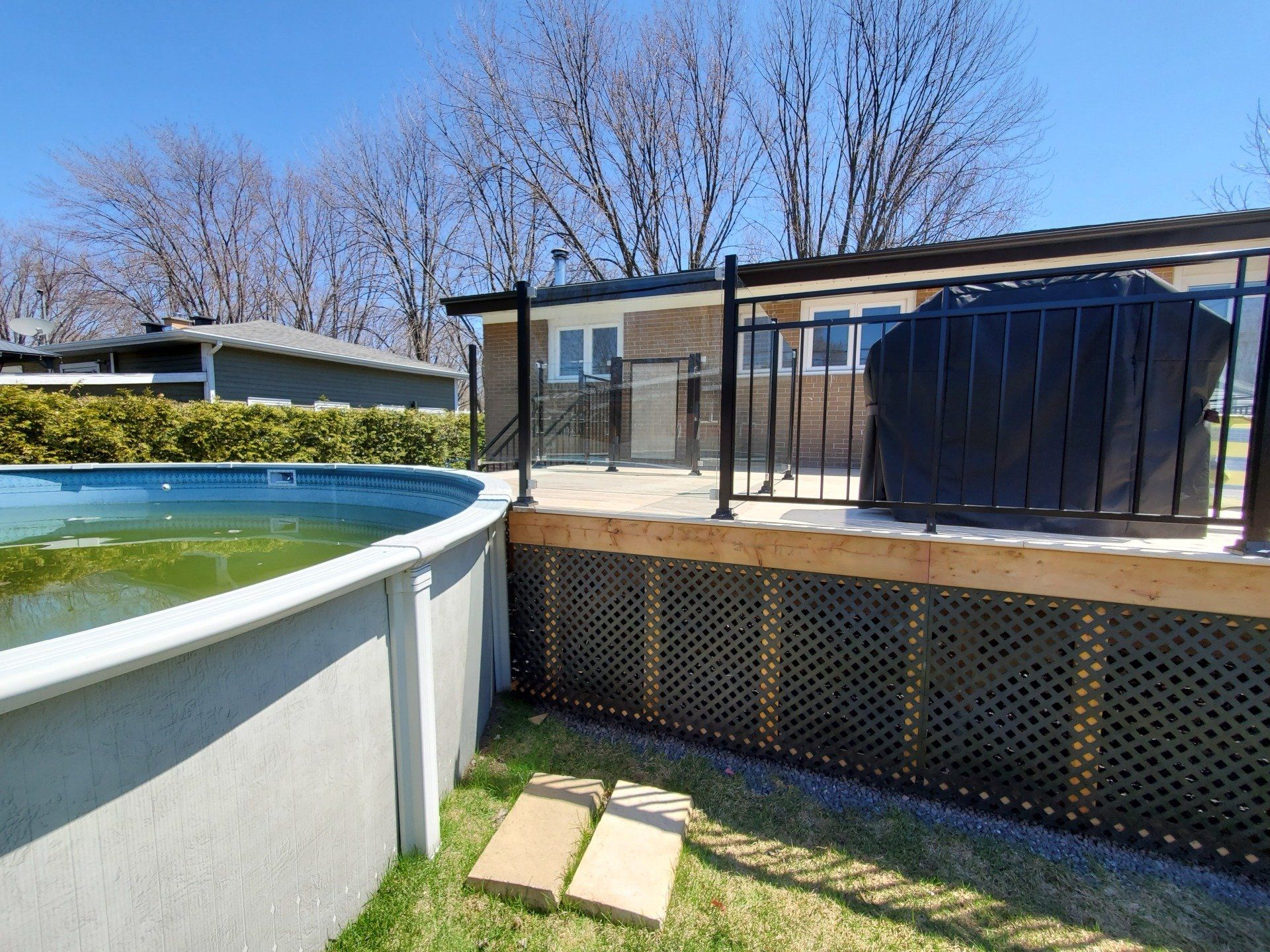 Une piscine est située à côté d'une terrasse dans une cour arrière.