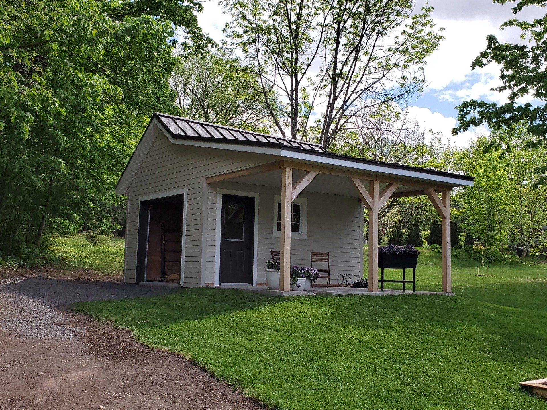 Un petit hangar blanc avec un porche et des arbres en arrière-plan