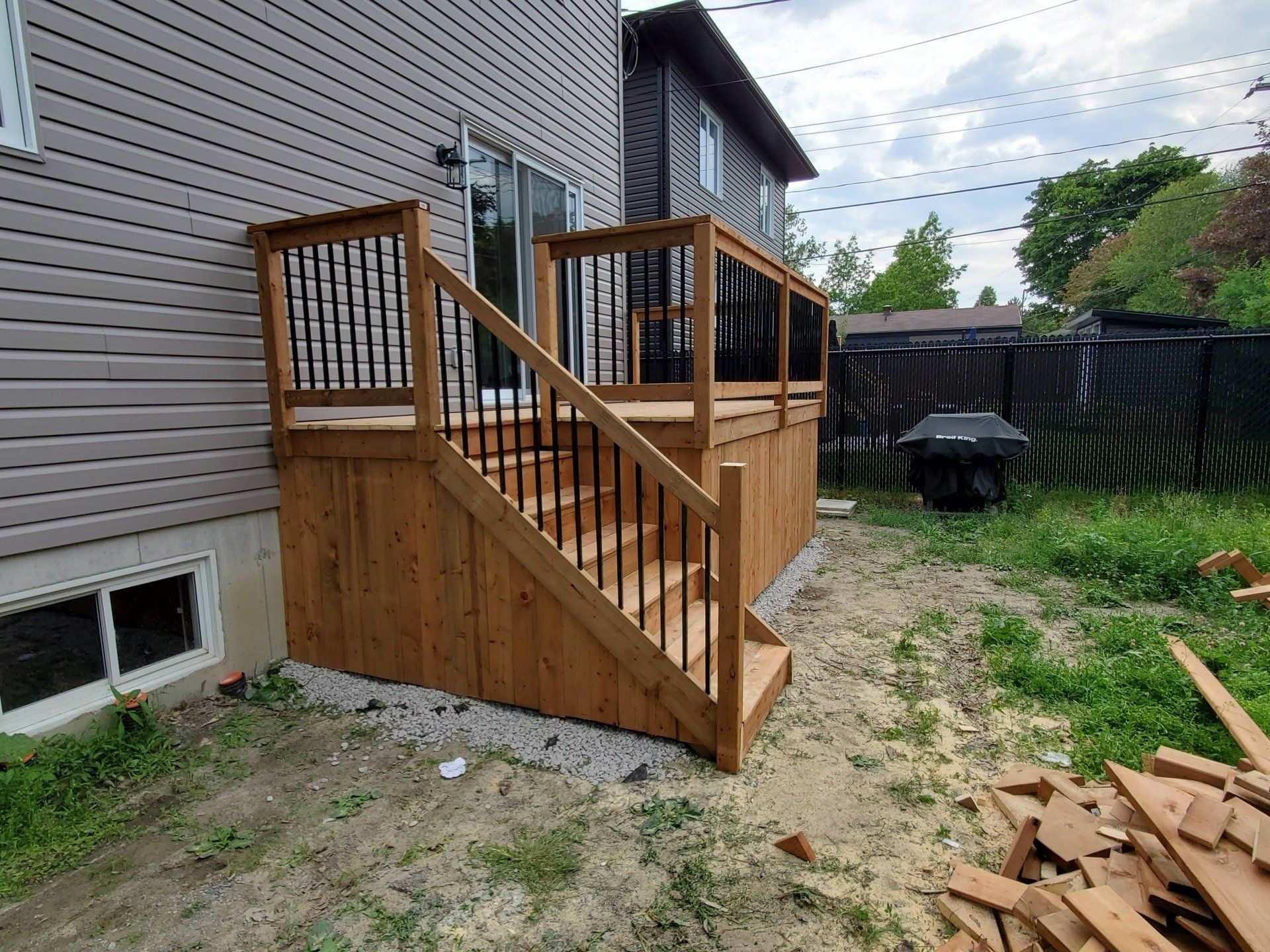 Une terrasse en bois avec des escaliers se trouve dans l'arrière-cour d'une maison.