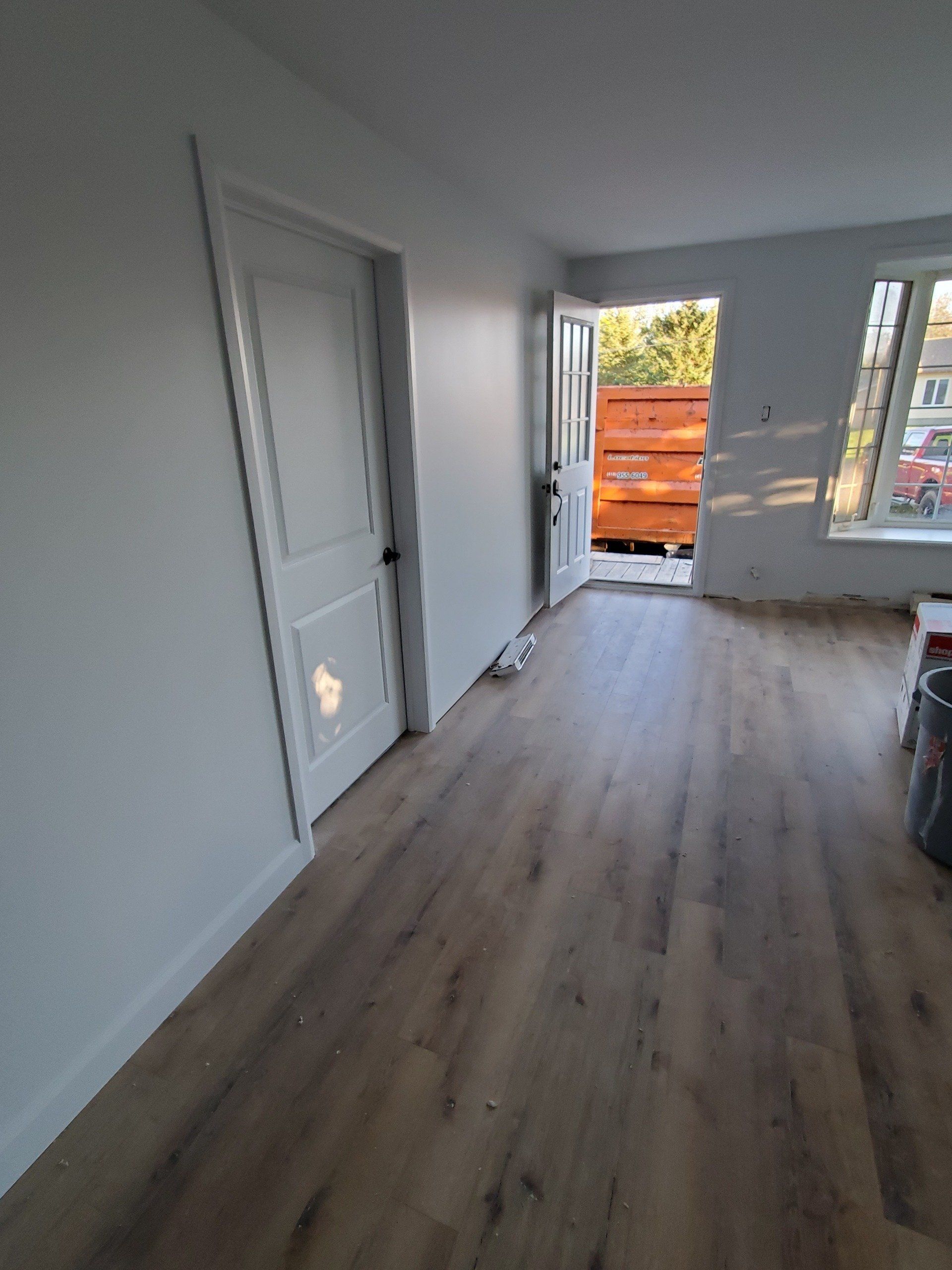 Un salon avec parquet et murs blancs.