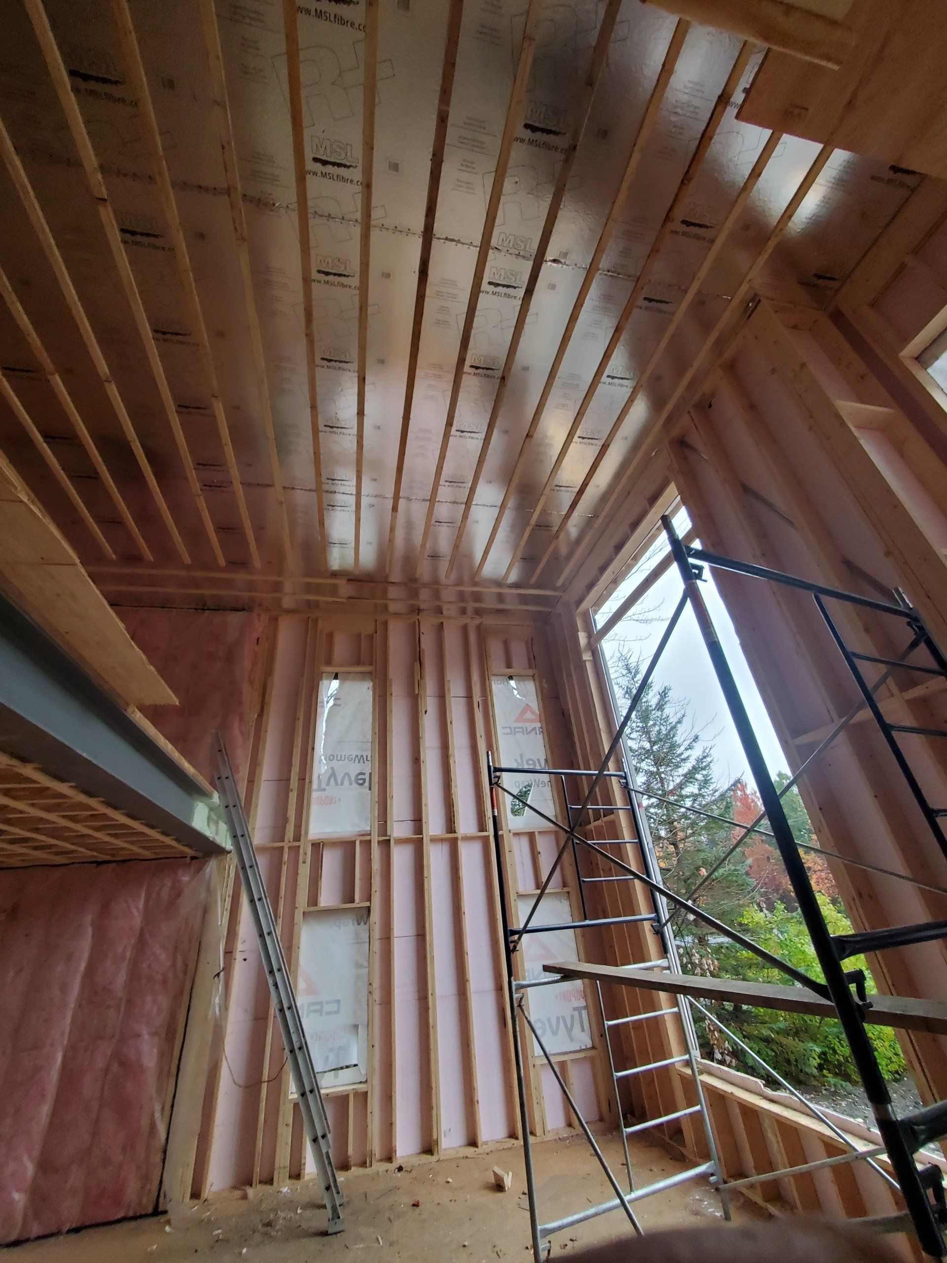 Une pièce dans une maison en construction avec une échelle et un échafaudage.