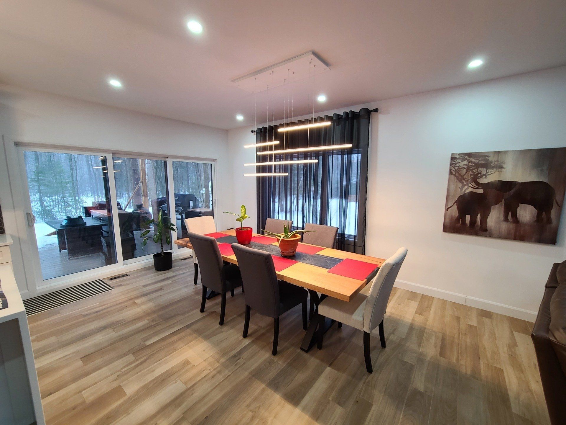 Une salle à manger avec une table et des chaises et un tableau d'éléphants sur le mur.