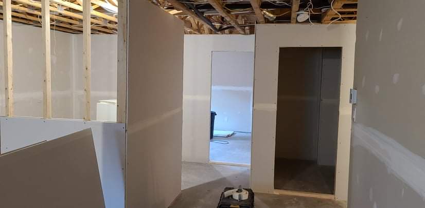 Une pièce avec des murs en plaques de plâtre et une porte dans une maison en construction.