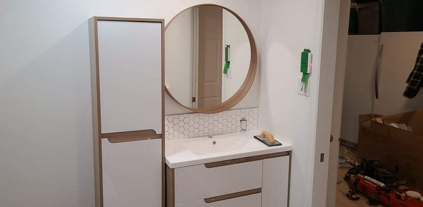 Une salle de bain avec lavabo, miroir et armoires.