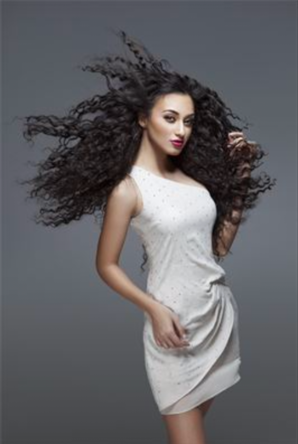 A woman in a white dress with long curly hair