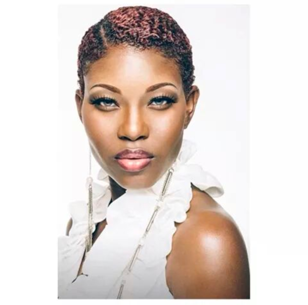 A woman with short red hair is wearing a white top and earrings