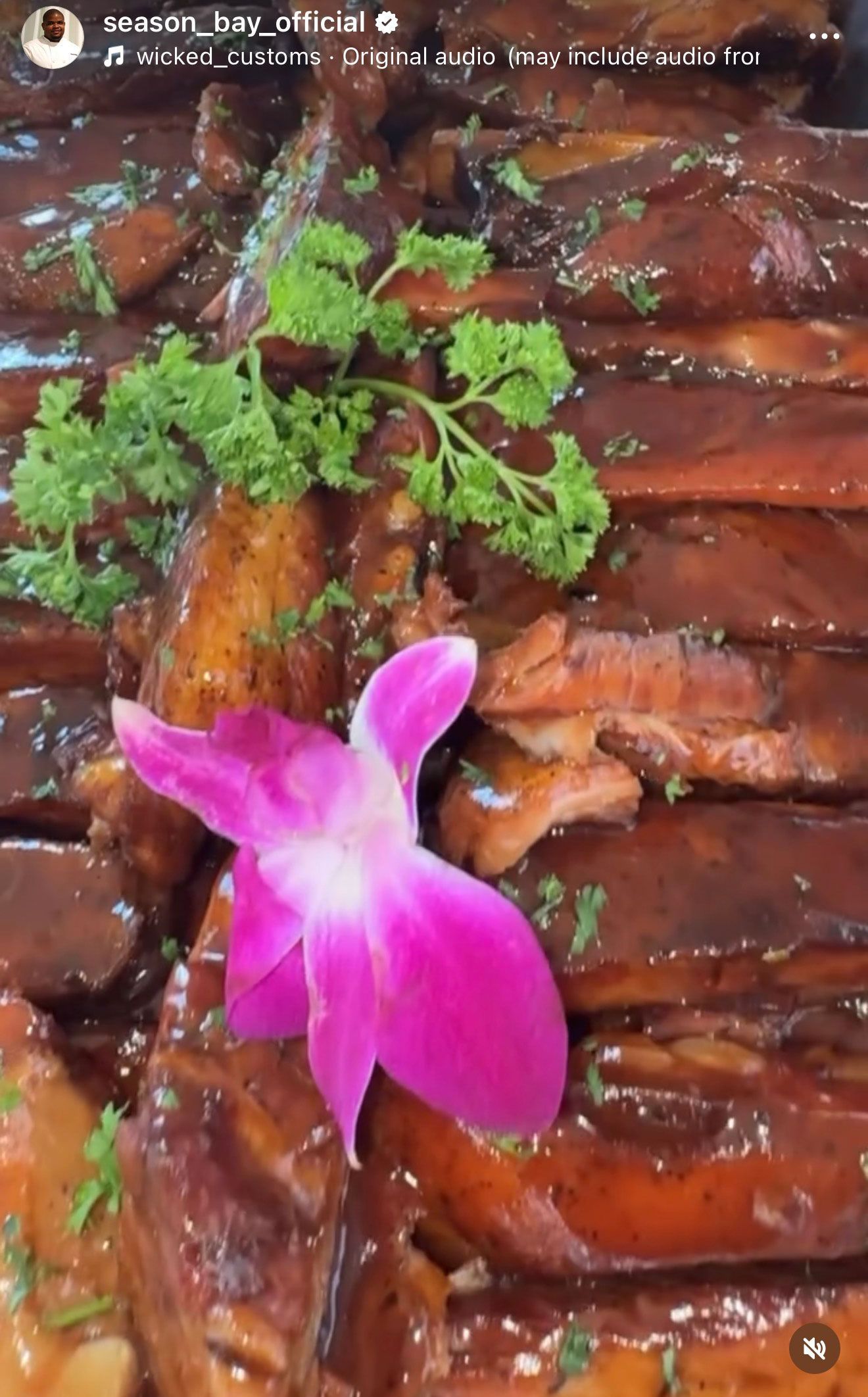 Rack of glazed ribs garnished with parsley and a pink orchid.