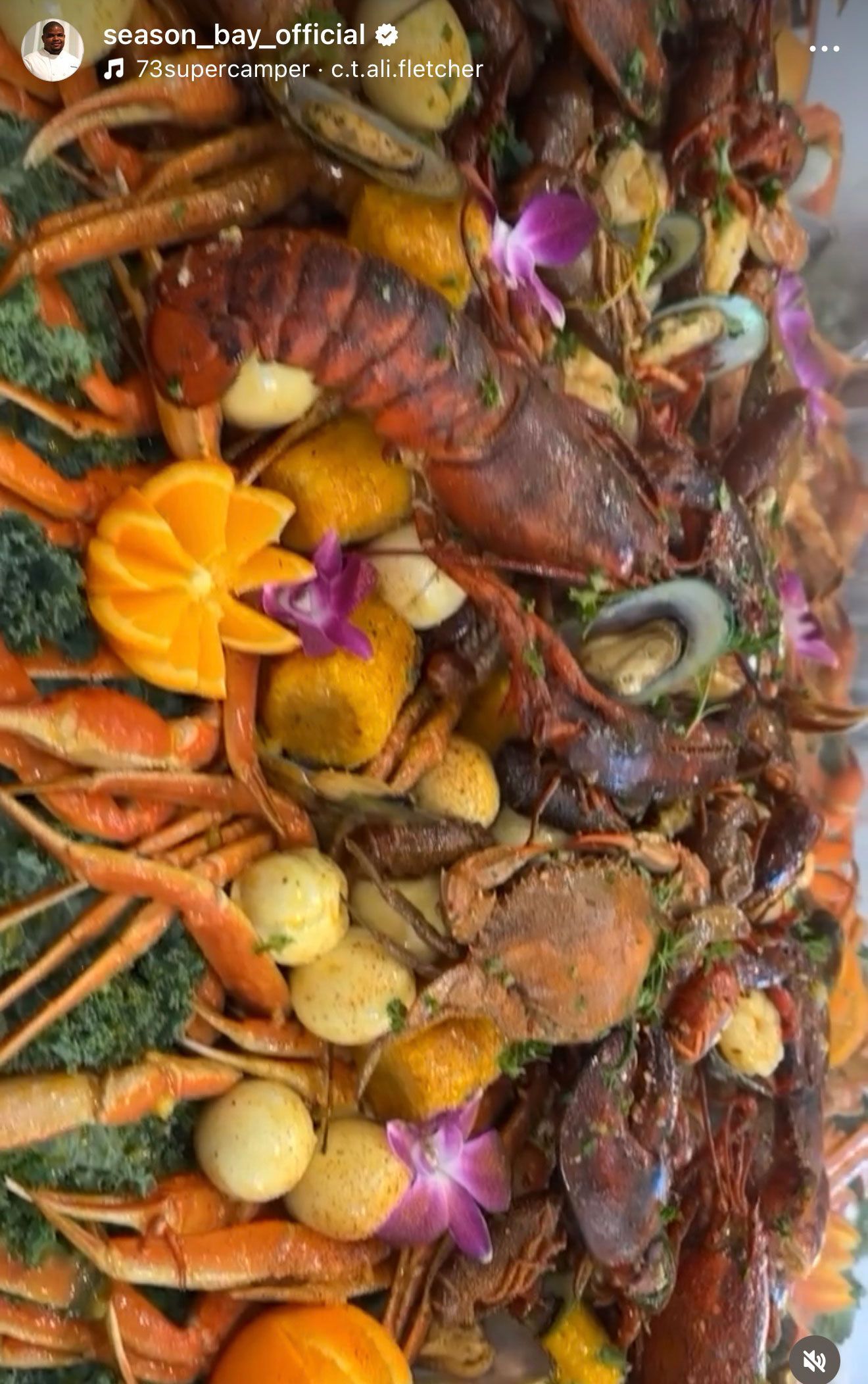Seafood platter with crawfish, shrimp, crab, scallops, and orange garnish.