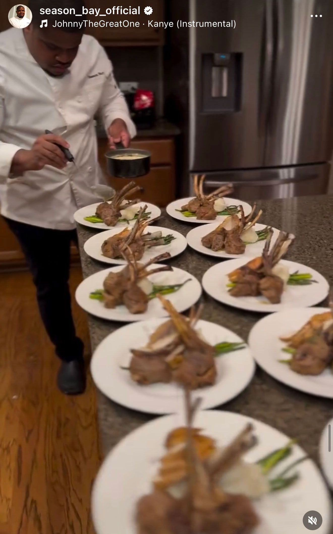 Chef plates lamb chops with sides on a countertop in a kitchen.