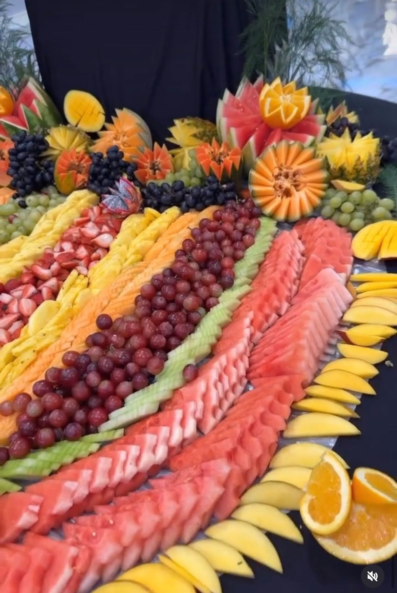 Fruit platter: colorful arrangement of sliced watermelon, grapes, mango, and carved orange and cantaloupe.