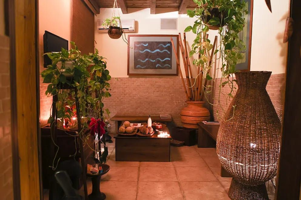 Una sala spa accogliente e a luce soffusa, con luci calde, decorazioni dai toni della terra, rigogliose piante da interno e un'atmosfera meditativa e serena.
