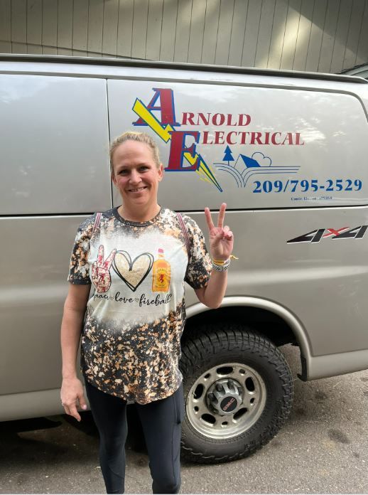 A woman stands in front of an arnold electrical van.