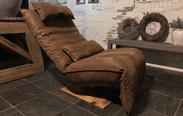 Een sfeervolle foto van de Chill Line Indi relaxfauteuil in zitstand. De stoel is stijlvol en comfortabel vormgegeven, met zachte bekleding en een ergonomisch ontwerp dat uitnodigt tot ontspannen zitten. De warme verlichting benadrukt de details en kleuren van de fauteuil, wat bijdraagt aan een rustgevende en gezellige ambiance in de ruimte