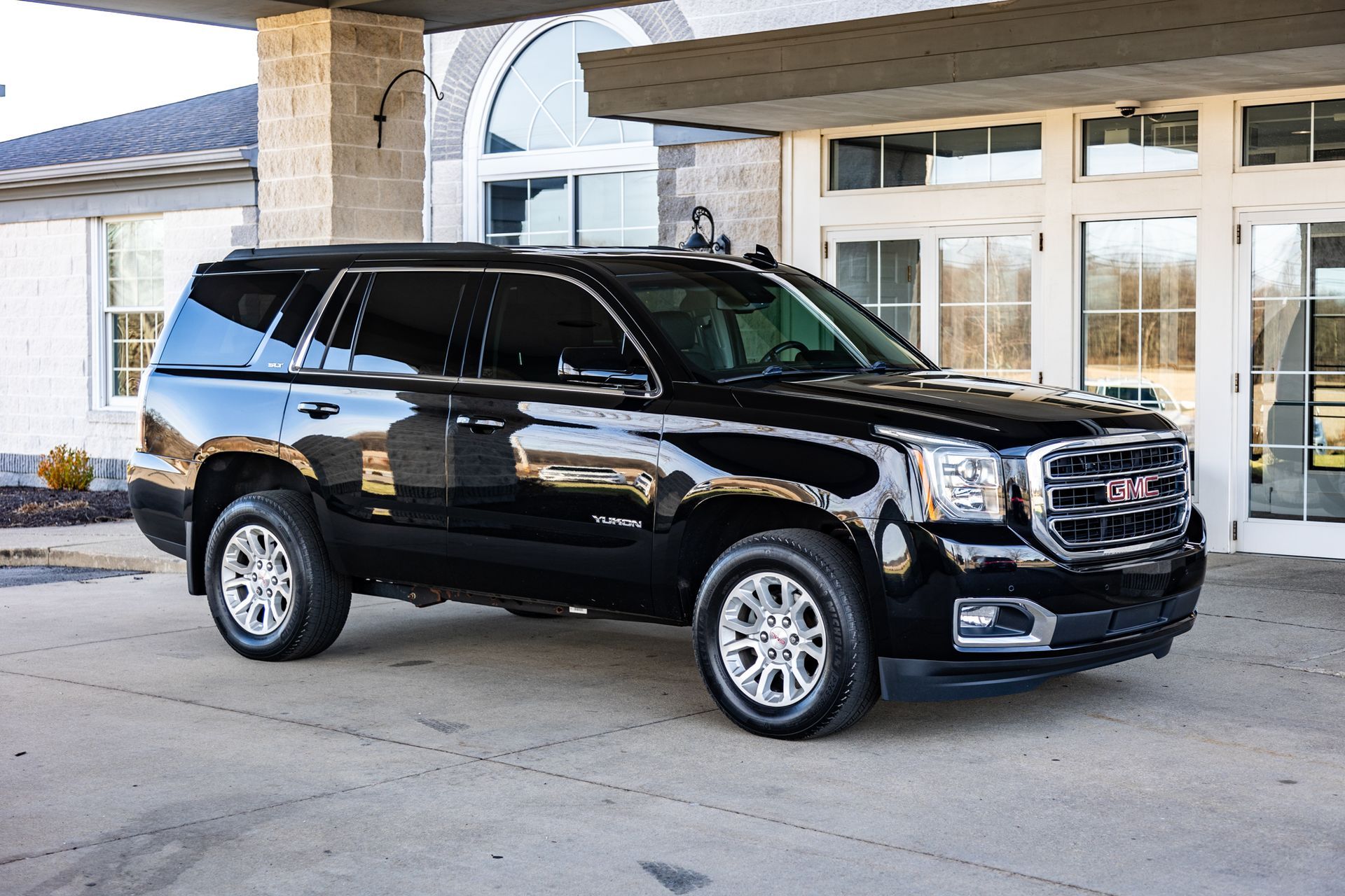 A black suv is parked in front of a building.