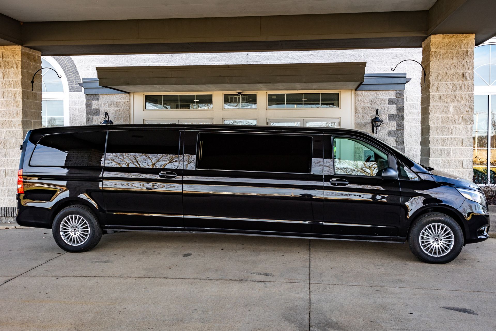 A black limousine is parked in front of a building.