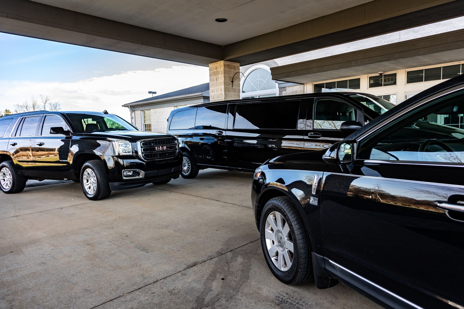 A row of black cars are parked in a parking lot.