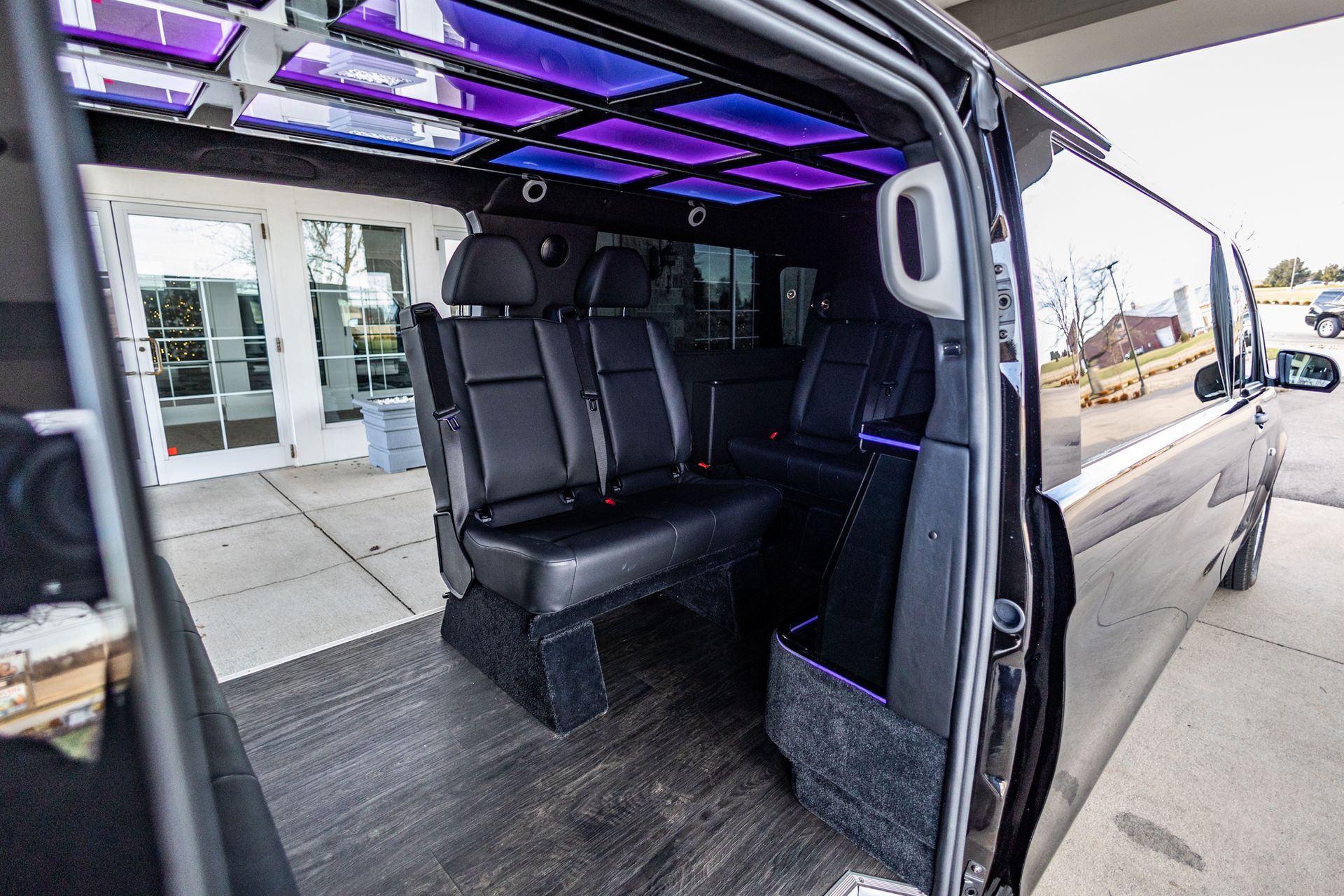 The inside of a van with the door open and purple lights on the ceiling.