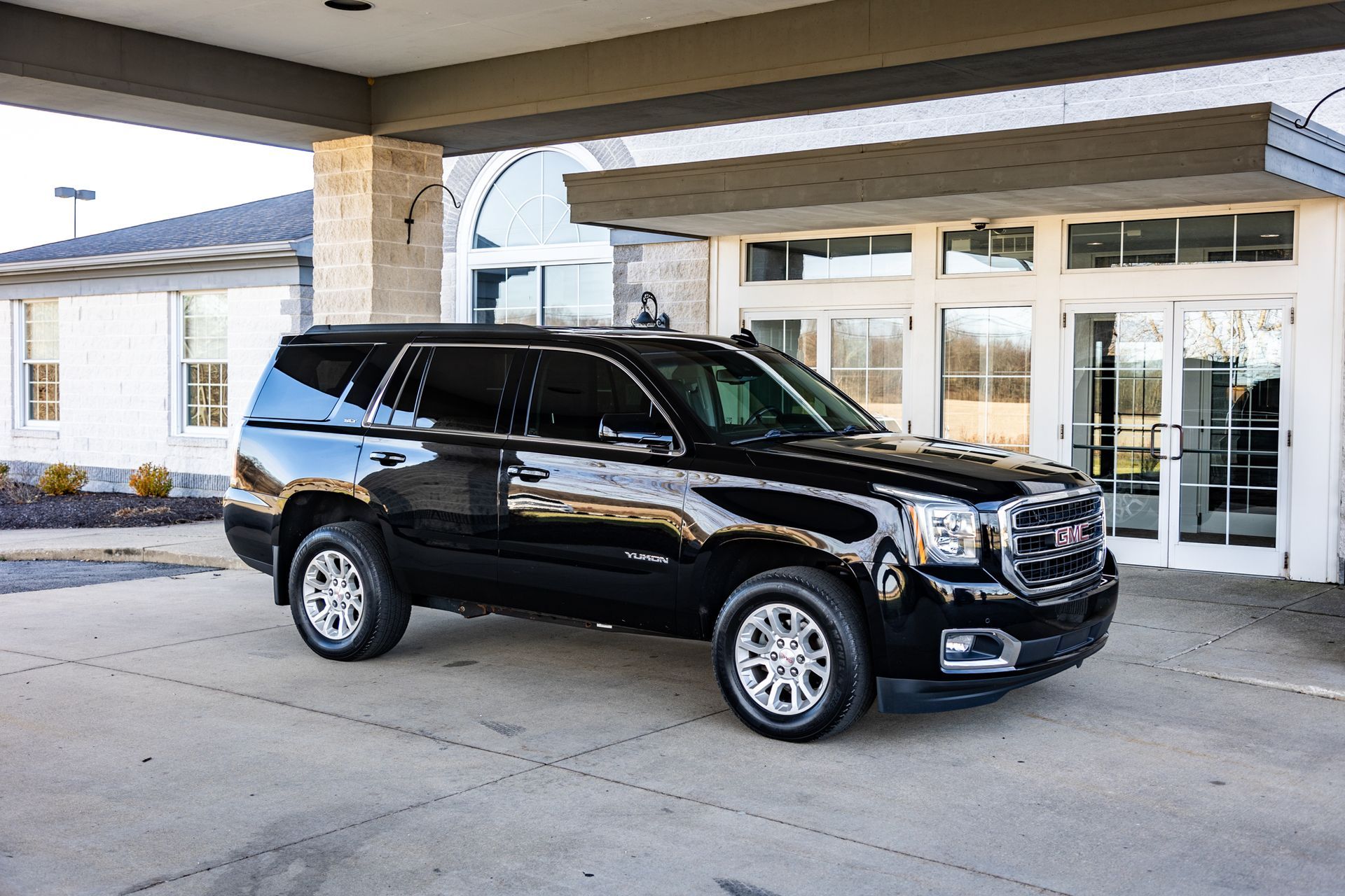 A black suv is parked in front of a building.