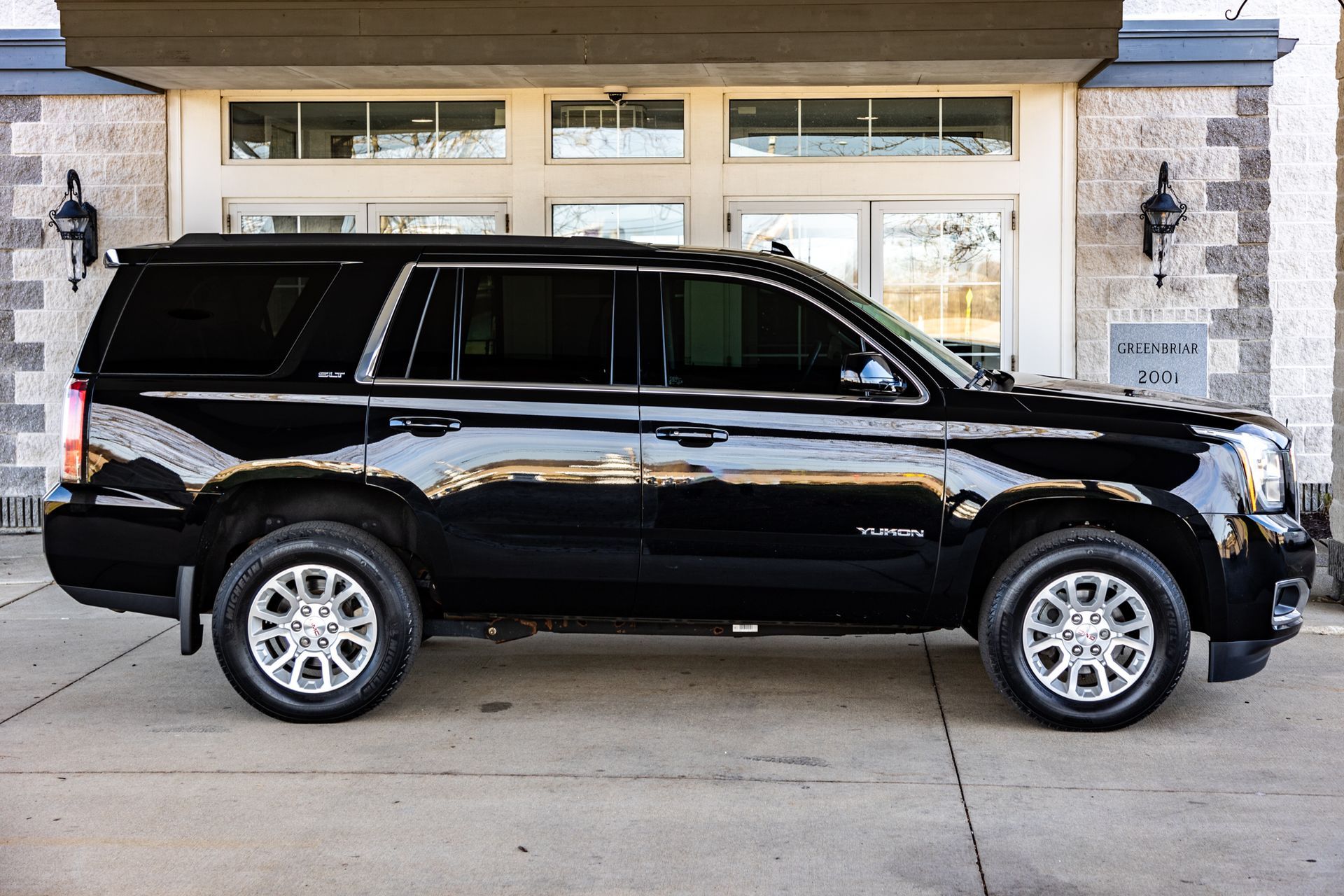 A black suv is parked in front of a building.