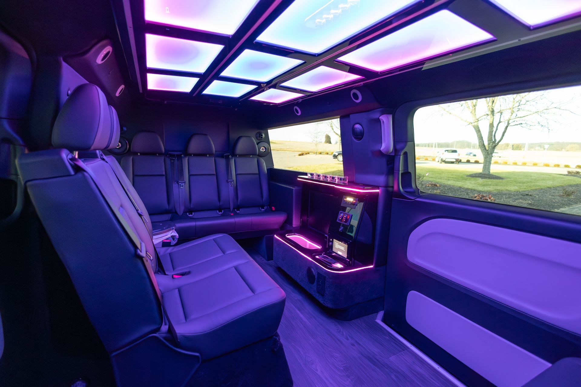 The inside of a limousine with purple lights on the ceiling.