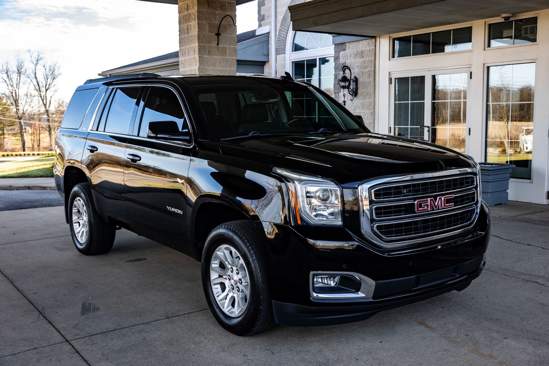 A black gmc yukon suv is parked in front of a building.