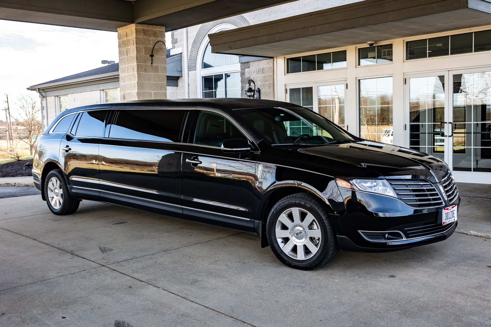 A black limousine is parked in front of a building.