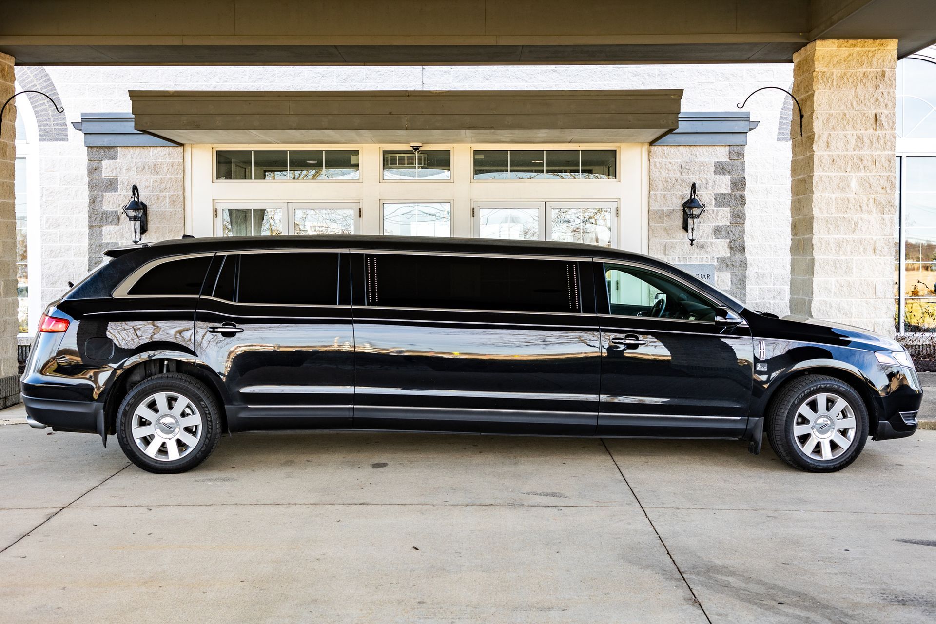 A black limousine is parked in front of a building.